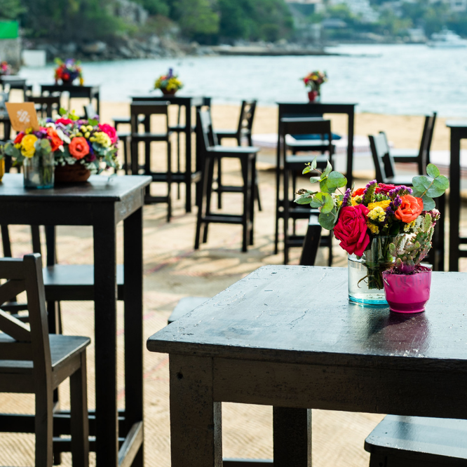 Decoración de mesas con flores coloridas en un evento frente a la playa.